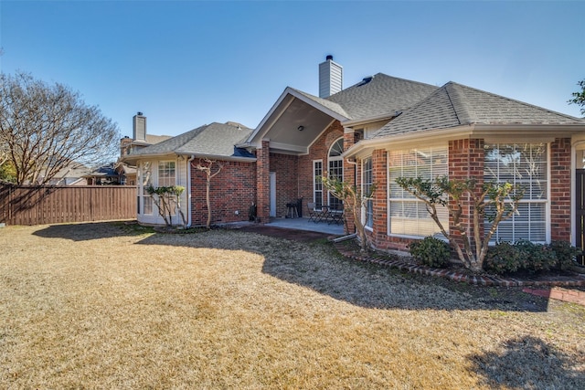 back of house featuring a yard, brick siding, a patio area, and fence