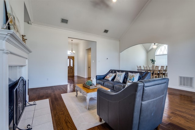 living room with wood finished floors, ornamental molding, a fireplace with flush hearth, and visible vents