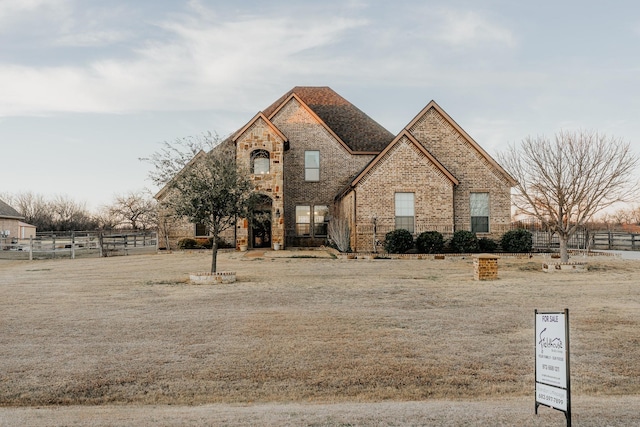 french provincial home with fence and brick siding