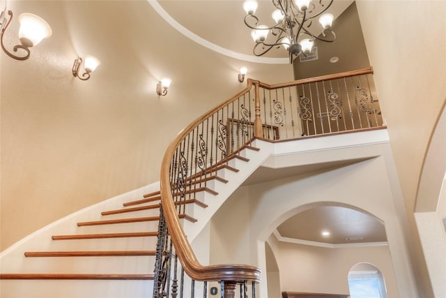 stairs with a towering ceiling, visible vents, and crown molding