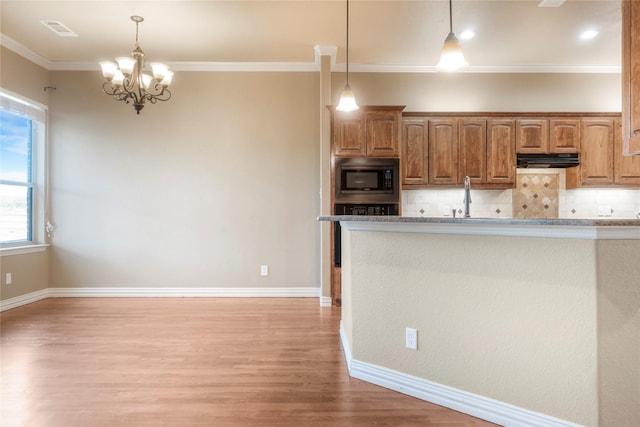 kitchen featuring under cabinet range hood, visible vents, built in microwave, and decorative backsplash