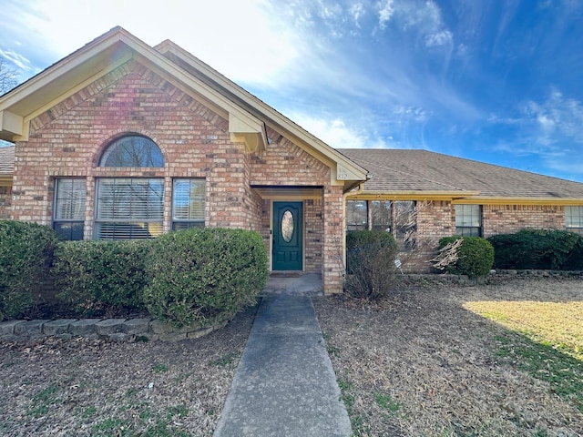 view of front of property featuring roof with shingles and brick siding