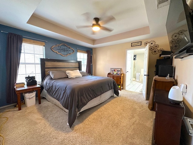 bedroom featuring ceiling fan, visible vents, a raised ceiling, and light colored carpet