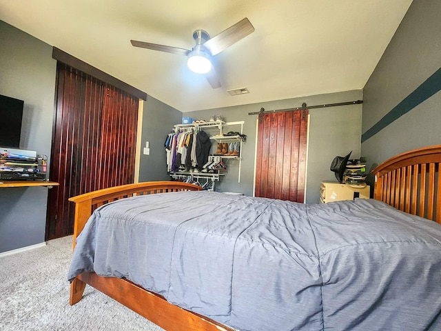 carpeted bedroom with baseboards, a barn door, visible vents, and a ceiling fan