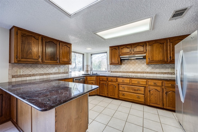 kitchen with stainless steel appliances, visible vents, a sink, a peninsula, and under cabinet range hood