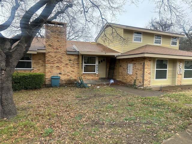 view of front of home featuring brick siding and a chimney