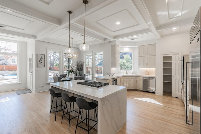 kitchen with a breakfast bar, coffered ceiling, a sink, light wood-style floors, and appliances with stainless steel finishes