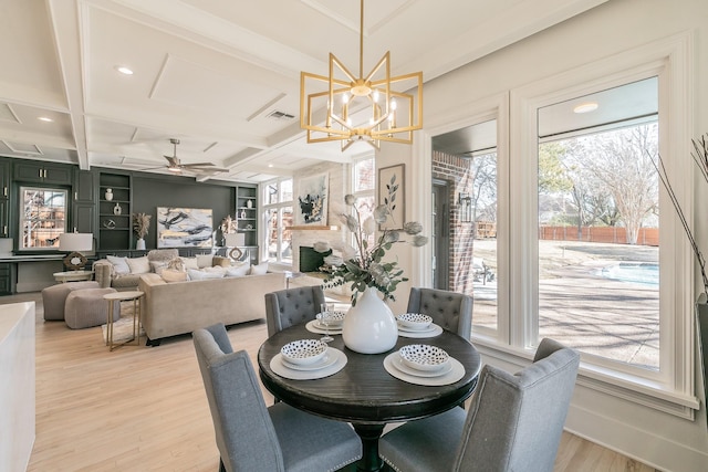 dining room featuring a large fireplace, coffered ceiling, built in features, beam ceiling, and light wood finished floors