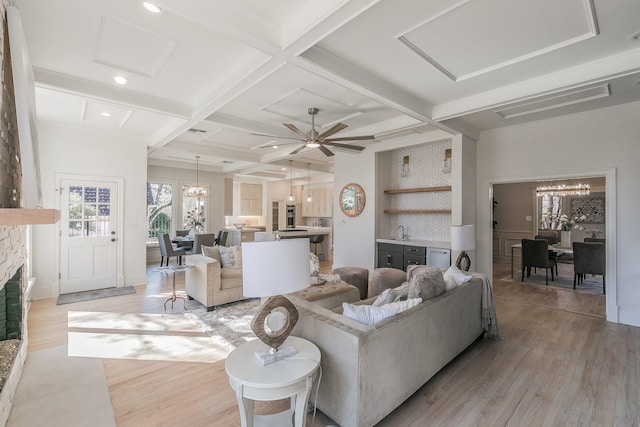 living room featuring beam ceiling, coffered ceiling, a fireplace, and light wood finished floors