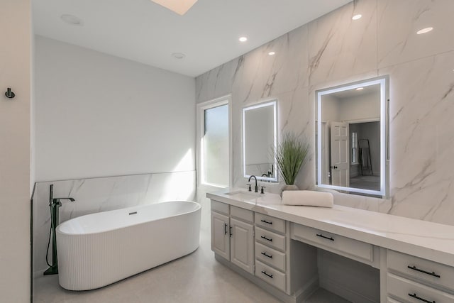 full bathroom featuring a freestanding bath, finished concrete floors, vanity, and tile walls