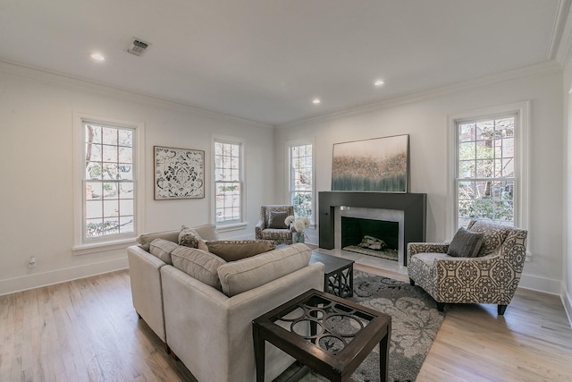 living room featuring a fireplace with flush hearth, visible vents, crown molding, and wood finished floors