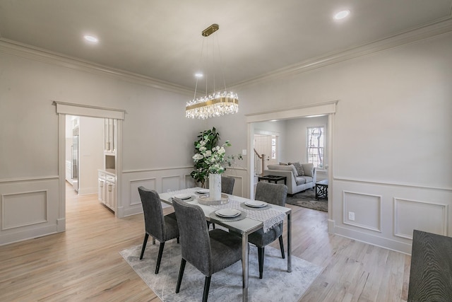 dining room featuring a chandelier, light wood-type flooring, and a decorative wall