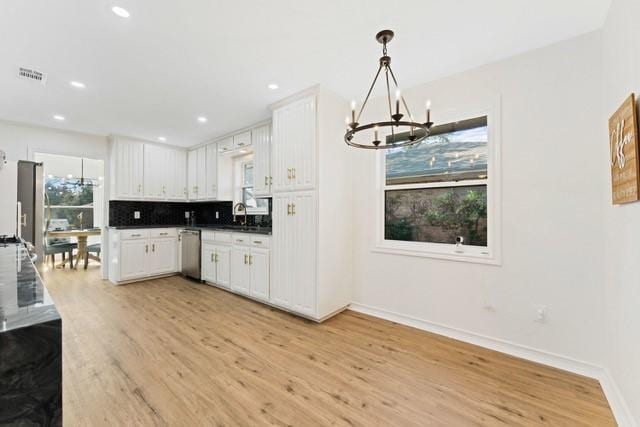 kitchen with a notable chandelier, light wood-style flooring, decorative backsplash, stainless steel dishwasher, and white cabinets