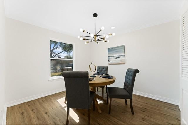 dining space with an inviting chandelier, baseboards, and wood finished floors