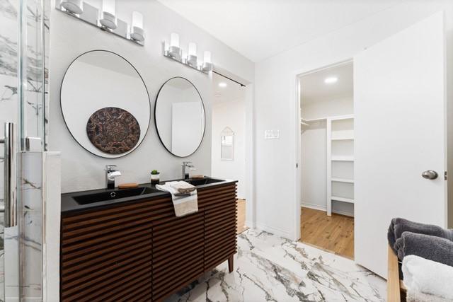 bathroom with marble finish floor, a spacious closet, an enclosed shower, and vanity