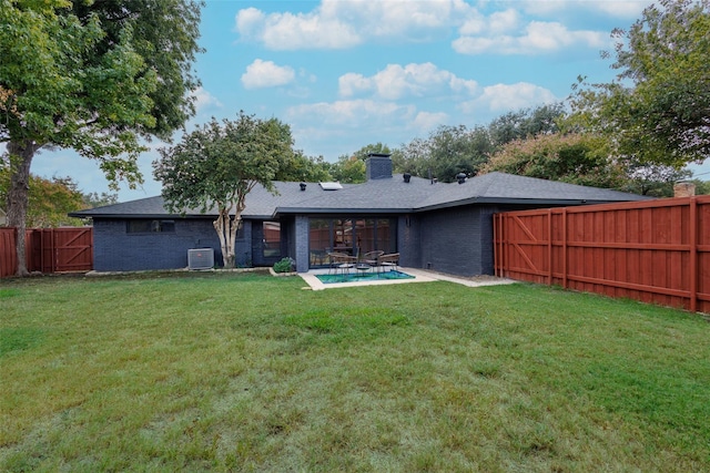 rear view of house with a patio, a fenced backyard, a yard, central air condition unit, and brick siding