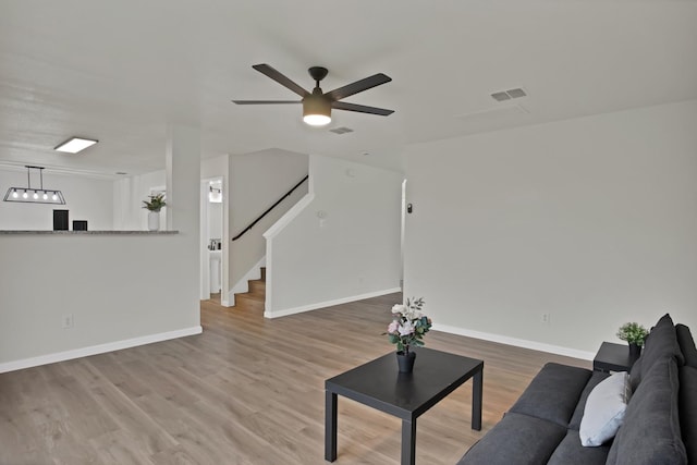 living room with stairway, baseboards, visible vents, and wood finished floors