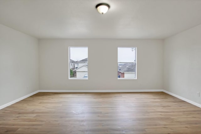 spare room with baseboards and wood finished floors