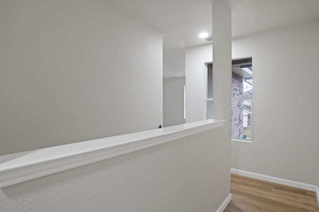 corridor featuring baseboards, wood finished floors, and recessed lighting