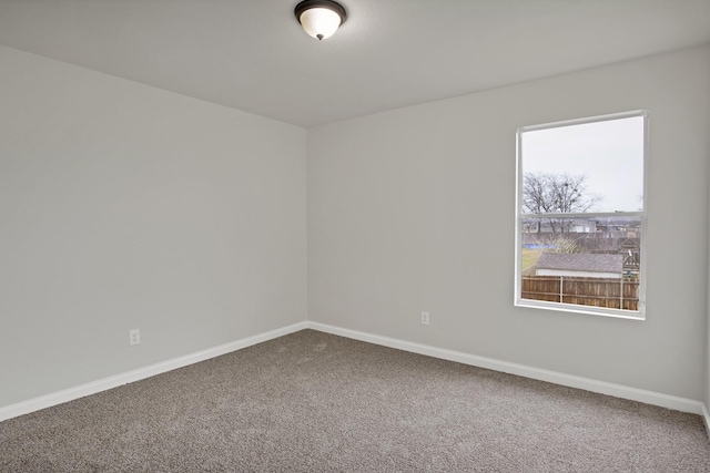 carpeted empty room featuring baseboards