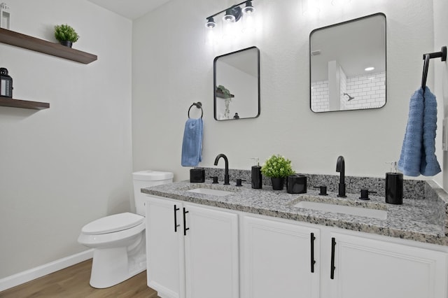 bathroom featuring double vanity, a sink, toilet, and wood finished floors