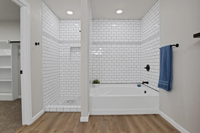 full bath with a bathtub, a tile shower, and wood finished floors