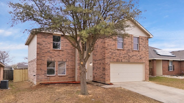 traditional-style home with an attached garage, central air condition unit, brick siding, fence, and concrete driveway