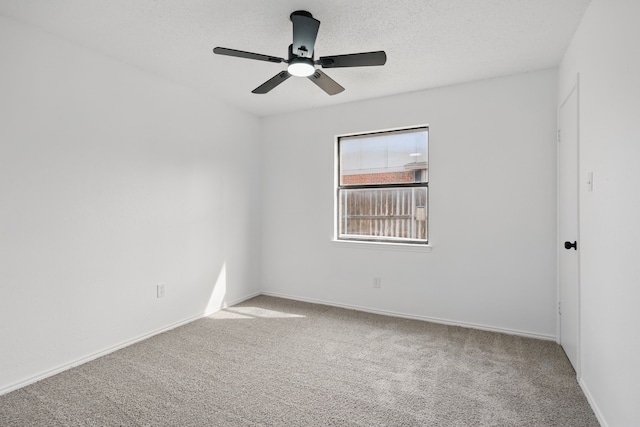 spare room with carpet floors, a ceiling fan, baseboards, and a textured ceiling