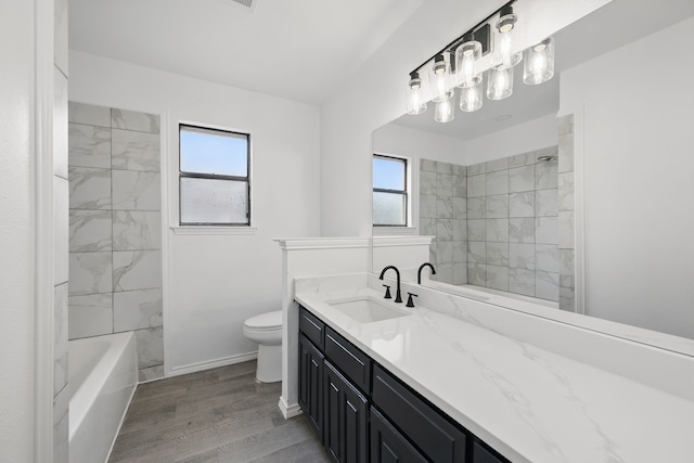 bathroom with toilet, washtub / shower combination, vanity, wood finished floors, and baseboards