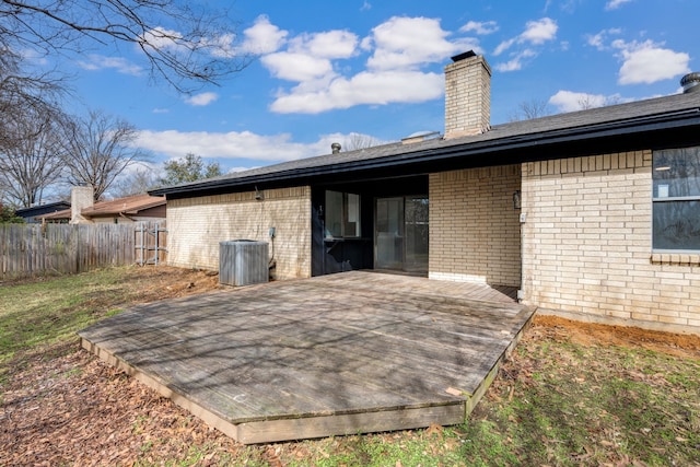 rear view of house with a chimney, fence, central AC, and brick siding