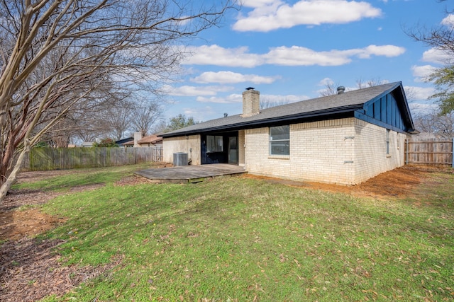 back of house featuring a wooden deck, a fenced backyard, a chimney, a yard, and brick siding