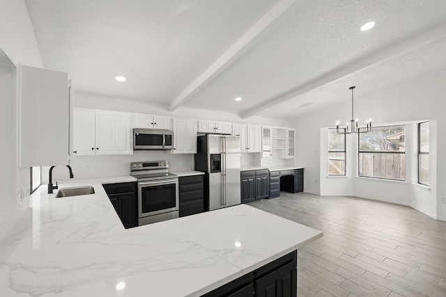 kitchen featuring light stone counters, stainless steel appliances, a peninsula, a sink, and wood tiled floor