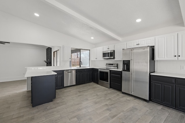 kitchen with vaulted ceiling with beams, stainless steel appliances, tasteful backsplash, a sink, and a peninsula