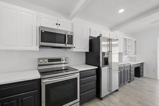 kitchen featuring light wood-style flooring, white cabinets, appliances with stainless steel finishes, backsplash, and beamed ceiling