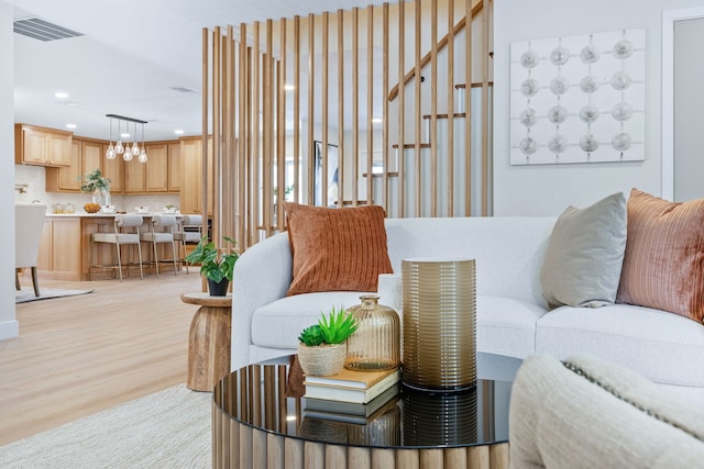 living room featuring a notable chandelier, recessed lighting, visible vents, light wood-style flooring, and stairs