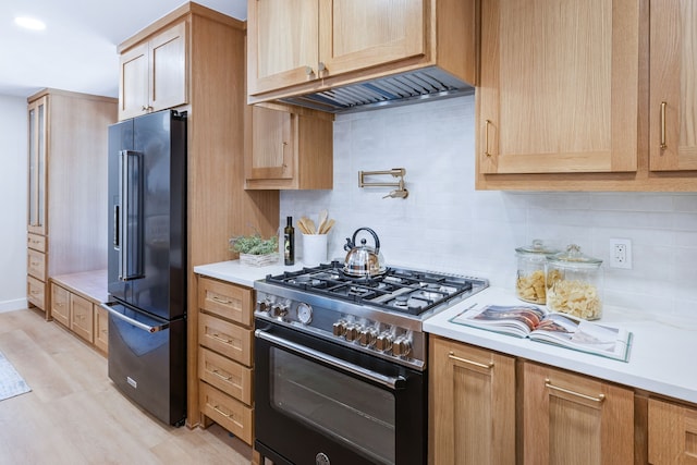 kitchen featuring high end appliances, light countertops, light wood-style flooring, decorative backsplash, and light brown cabinets