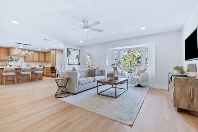 living area with light wood-type flooring, baseboards, a ceiling fan, and recessed lighting