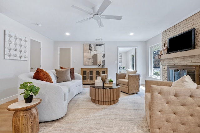 living area with baseboards, light wood-style floors, ceiling fan, a brick fireplace, and recessed lighting