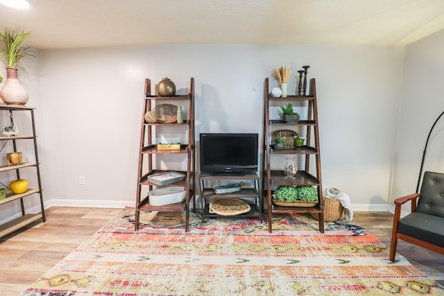 living area with a textured ceiling, baseboards, and wood finished floors