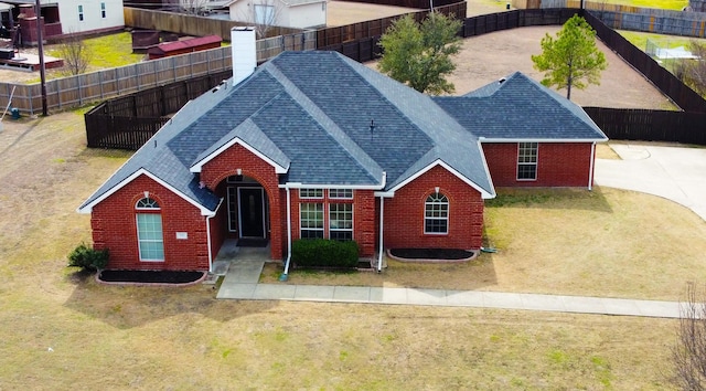 exterior space with a shingled roof, fence, and brick siding