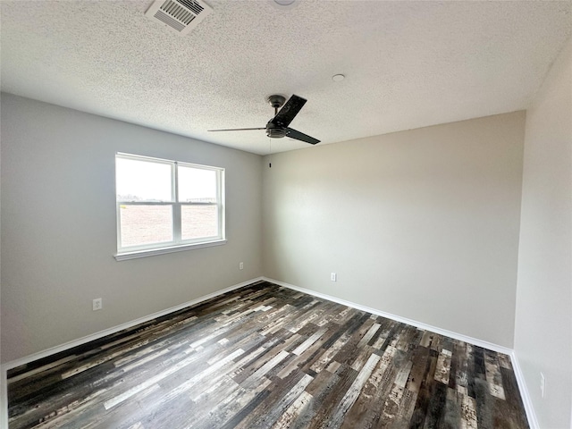 empty room with a textured ceiling, ceiling fan, visible vents, baseboards, and dark wood finished floors