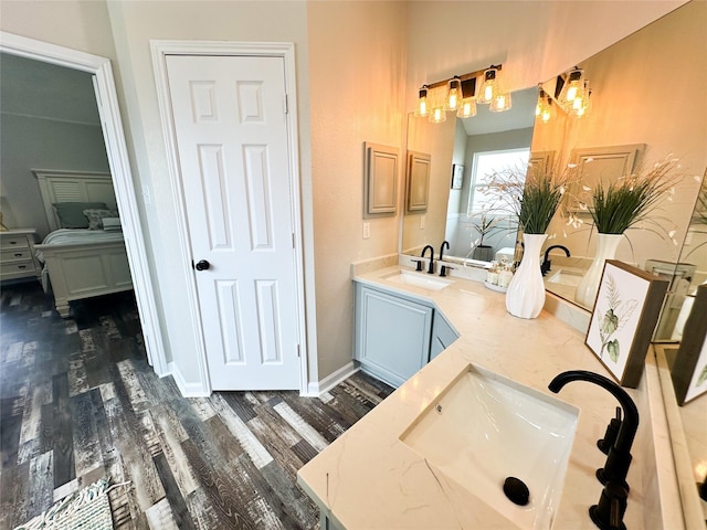 bathroom featuring double vanity, baseboards, a sink, and wood finished floors