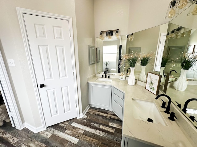 bathroom with double vanity, a sink, baseboards, and wood finished floors