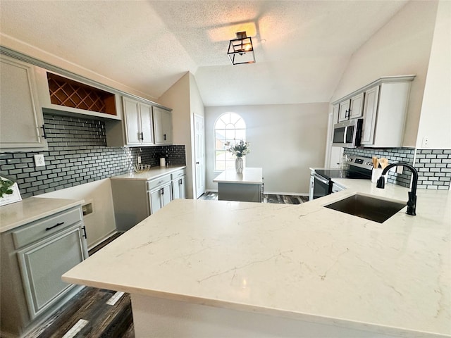 kitchen featuring stainless steel appliances, a center island, vaulted ceiling, and a sink