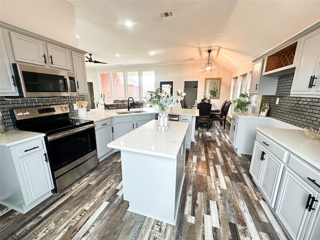 kitchen with dark wood-style flooring, visible vents, appliances with stainless steel finishes, a sink, and a peninsula