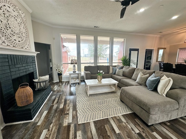 living area with a brick fireplace, visible vents, dark wood-type flooring, and ornamental molding