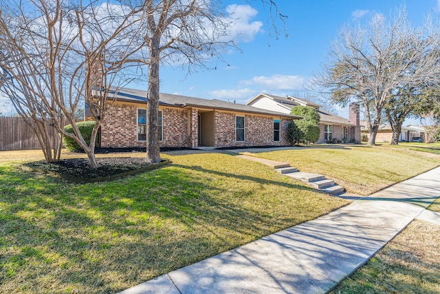 ranch-style house featuring a front yard, brick siding, and fence