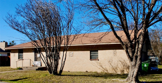 view of home's exterior with brick siding and a lawn