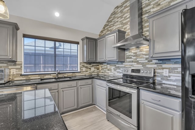 kitchen featuring gray cabinetry, a sink, stainless steel range with electric cooktop, vaulted ceiling, and wall chimney exhaust hood