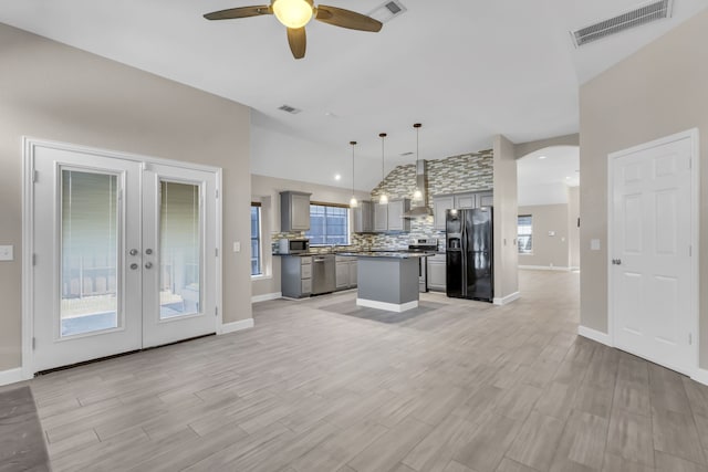 kitchen with wall chimney range hood, visible vents, stainless steel appliances, and gray cabinetry